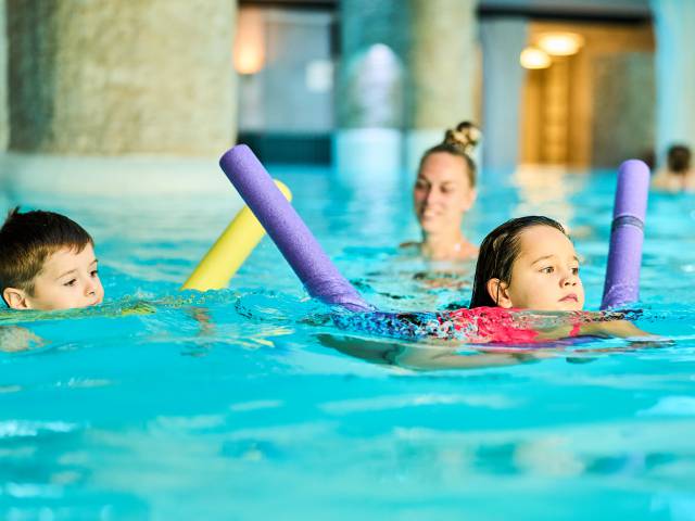 Kinder mit Poolnudel beim Schwimmkurs